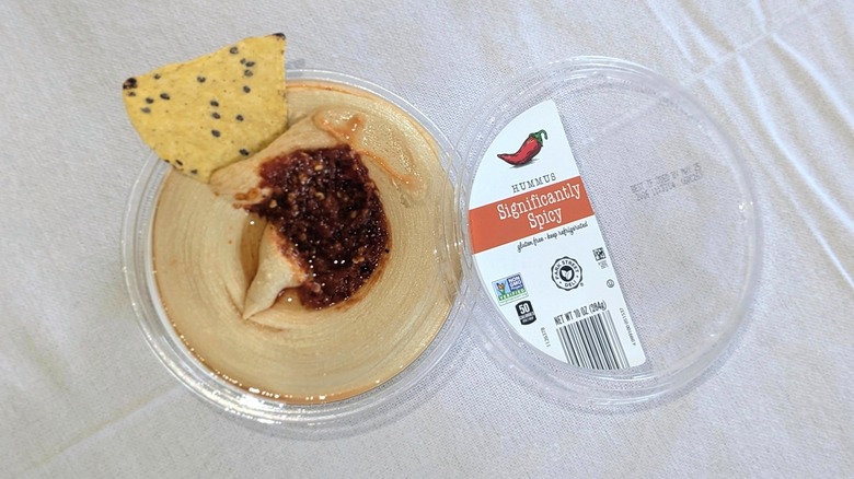 A container of Park Street Deli Significantly Spicy Hummus with a chip in it