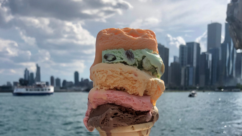 A colorful stack of ice cream sits atop a cone, with the Chicago skyline in the background.