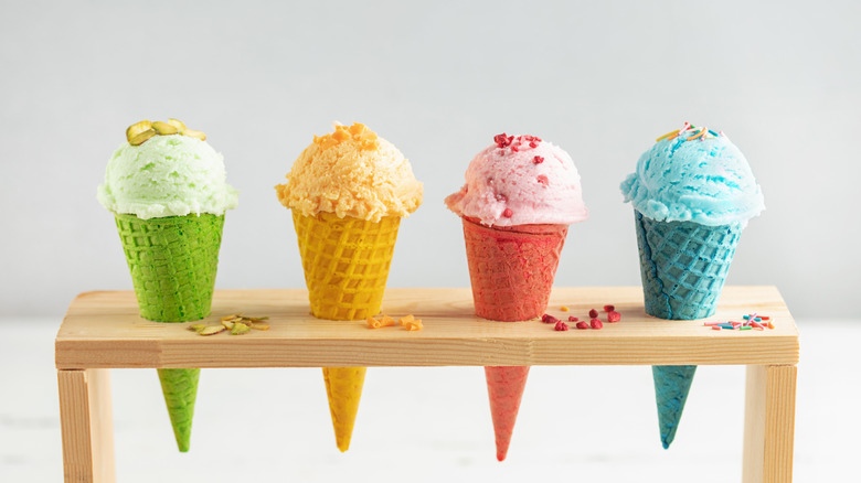 A stand holding four different colors of ice creams and cones.