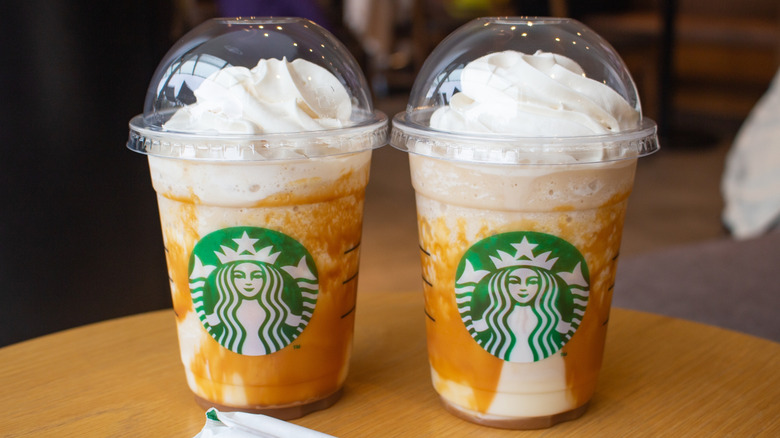 Two Starbucks Caramel Frappuccinos on wooden surface