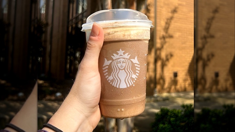 Hand holding coffee Frappuccino with foam topping from Starbucks