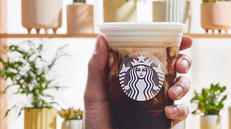 Hand holding cold brew drink with cold foam from Starbucks