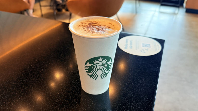 Starbucks Cozy Latte in a paper cup on the corner of counter inside the cafe