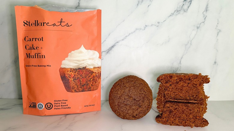 Stellar Eats Carrot Cake Mix package next to two carrot cake cupcakes on marble surface