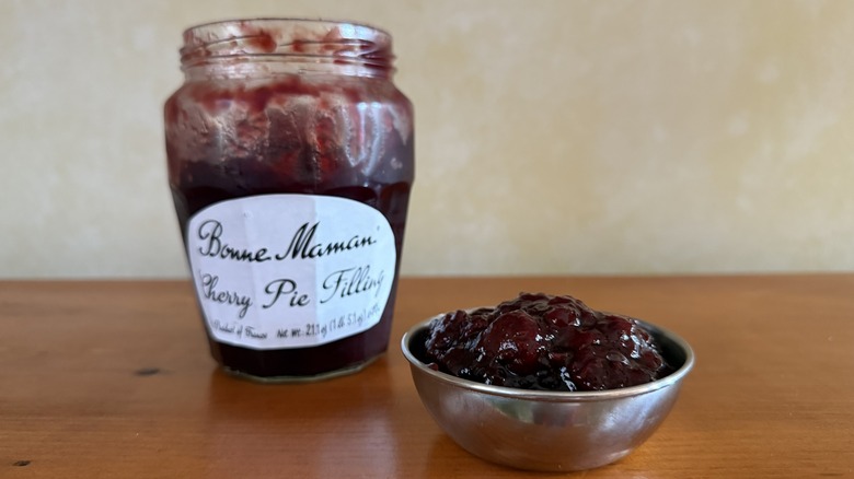 Bowl with cherry pie filling in front of glass jar