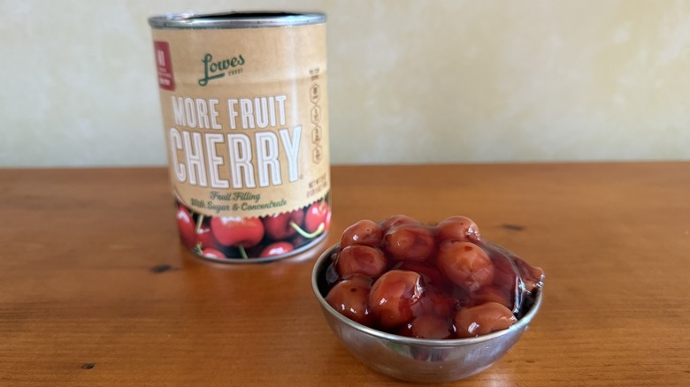 Bowl of cherry pie filling with plenty of fruit in front of can