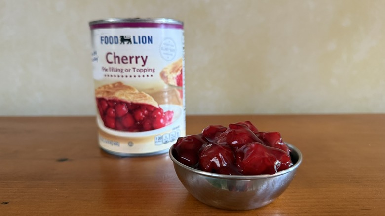 Bowl of darkly hued cherry pie filling in front of can