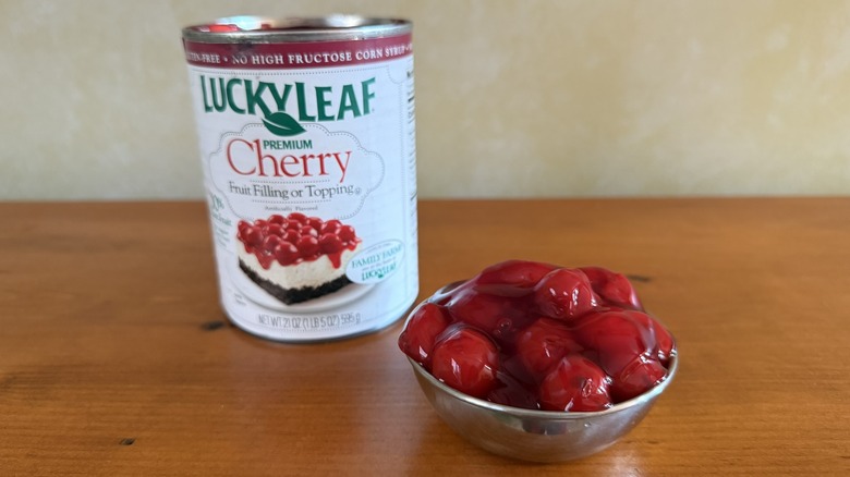Bowl of cherry pie filling with large whole cherries in front of can