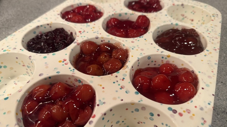 Muffin tray with cherry pie filling in eight cups