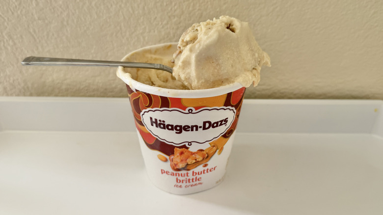 Häagen-Dazs Peanut Butter Brittle scoop on a spoon nestled on a pint of ice cream