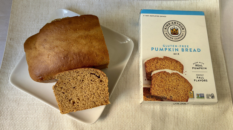 Baked loaf King Arthur Baking Company Gluten-Free Pumpkin Bread and Muffin Mix with a slice on a plate next to box