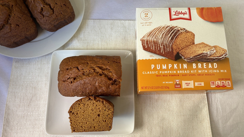Baked loaf Libby's Pumpkin Bread with slice on plate and box plus two more loaves beside it