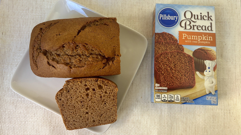 Baked loaf Pillsbury Pumpkin Quick Bread & Muffin Mix with a slice on a plate next to box