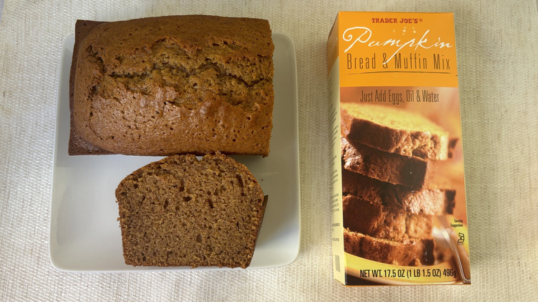 Baked loaf Trader Joe's Pumpkin Bread & Muffin Mix with a slice on a plate next to box