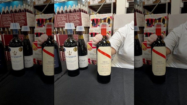Person presenting a wine bottle at a sampling event at Sam's Club