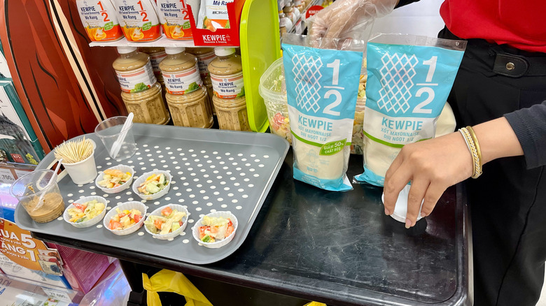 Hands arranging a display of samples at grocery store