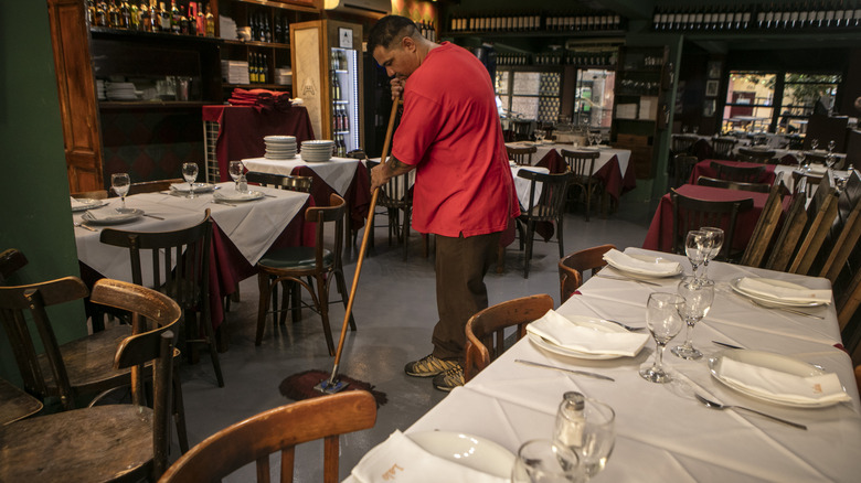Employee mopping restaurant before close