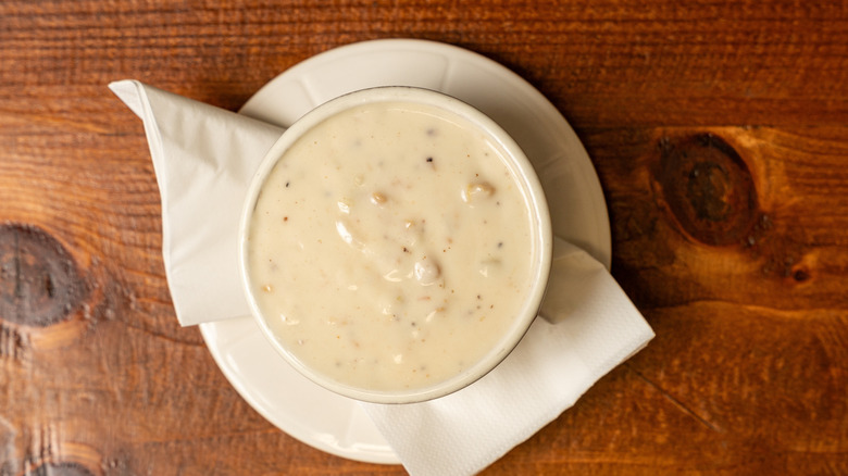 Clam chowder on white plate on wooden surface