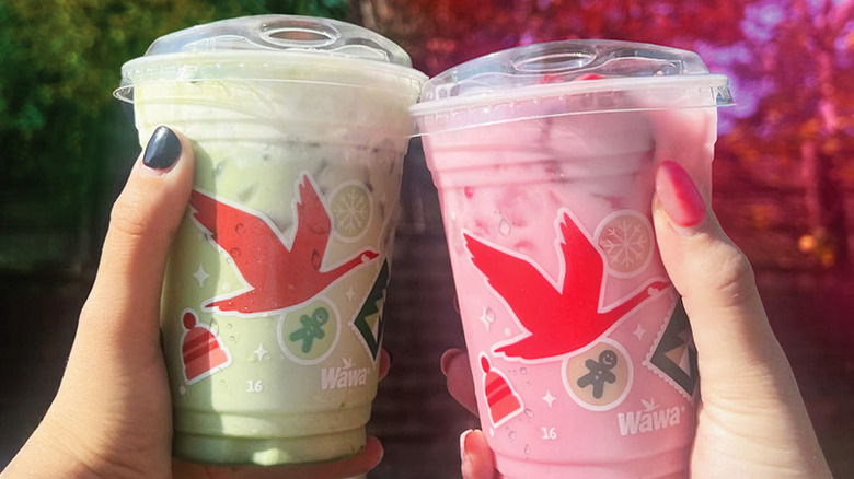 Two women's hands holding two different Wawa drinks in plastic cups