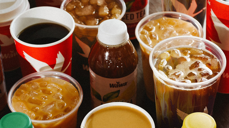several Wawa drinks on a counter served in paper and plastic cups and a bottle