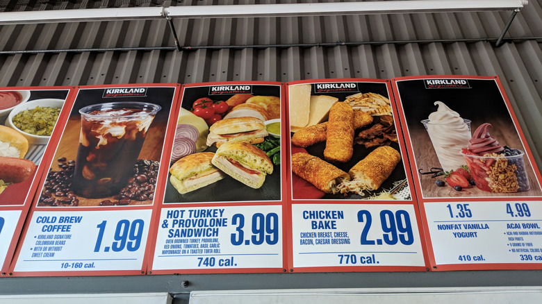 A view of the food court offerings at Costco with cold coffee, hot turkey sandwich, chicken cake and vanilla yogurt displayed