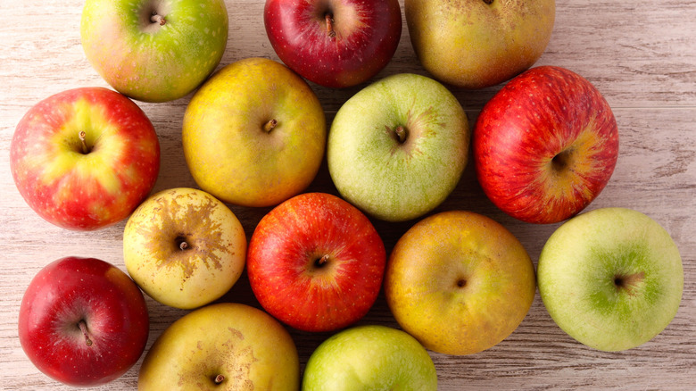 Different types of apple arranged on a light-colored wood table