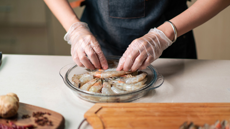 hands arranging shrimp in pie plate