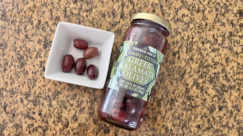 Jar of Jumbo Pitted Greek Kalamata Olives with olives in a small dish