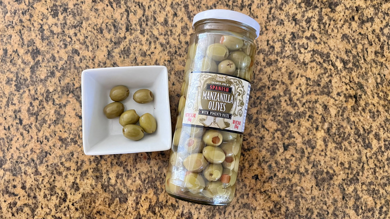 Jar of Spanish Manzanilla Olives with Pimento Paste with olives in a dish