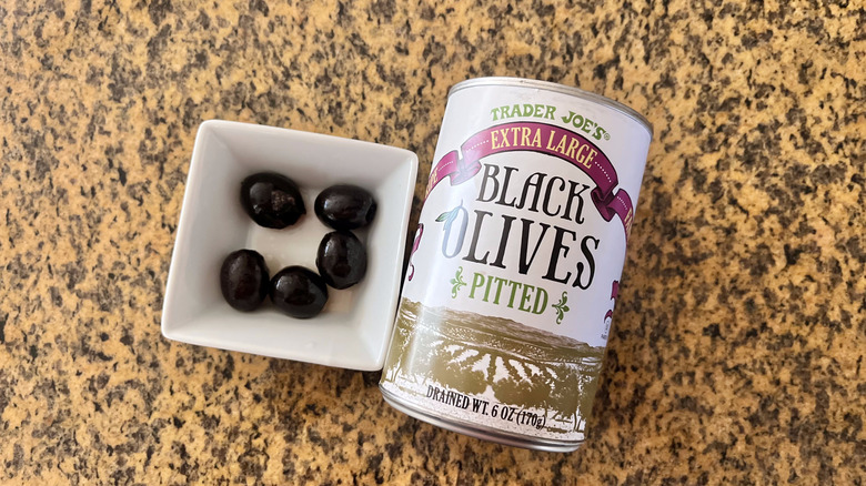 Can of Extra Large Black Pitted Olives with olives in a white dish