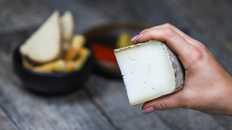 Hand holding wedge of Garrotxa cheese