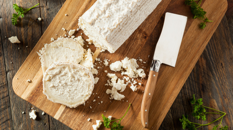Goat cheese log on cutting board with knife