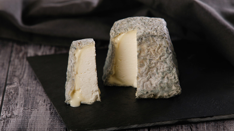 Valençay goat cheese on a black plate with slice removed to show interior