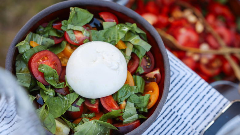 Overhead shot of burrata topping tomato and basil salad