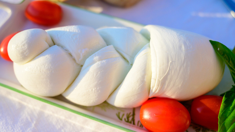 Braided mozzarella presented alongside tomatoes and basil