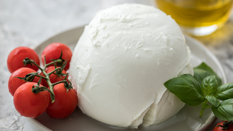 Buffalo mozzarella surrounded by cherry tomatoes, basil, and oil decanter
