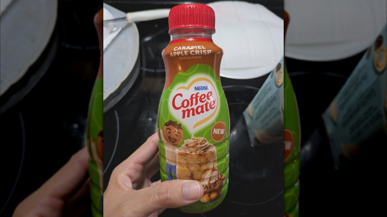 person holding coffee mate caramel apple crisp creamer