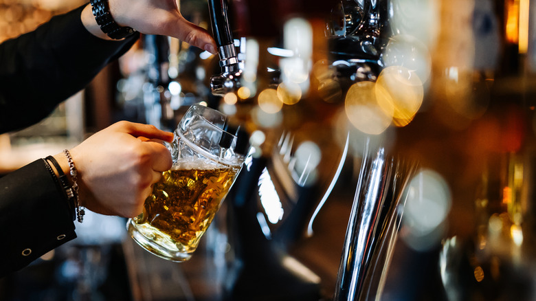 Bartender pouring beer from tap into glass