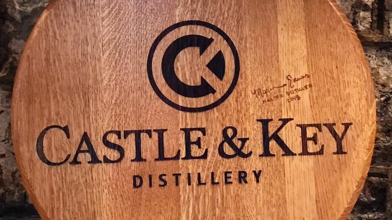 A wooden sign showcasing the Castle & Key logo and a signature from the master distiller