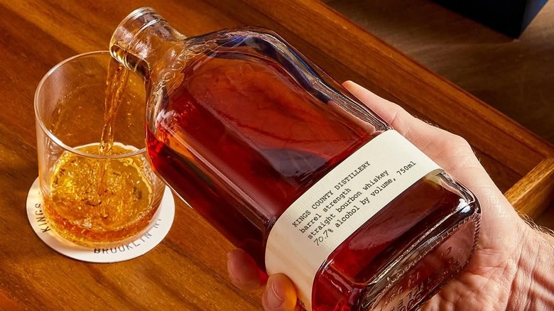 A bottle of Kings County Distillery bourbon being poured from the hand into a glass