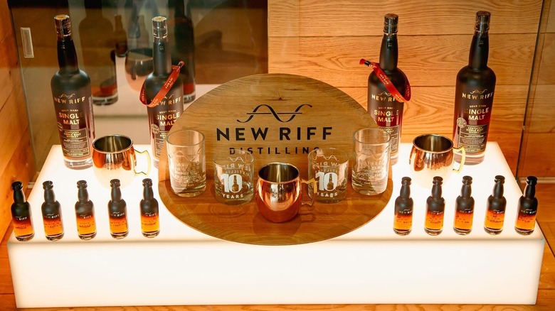 A range of New Riff Distilling bottles and glasses showcased on a lit up shelf
