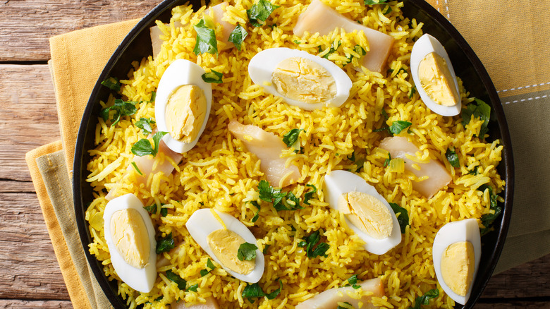overhead view of kedgeree with golden basmati, smoked cod or haddock, and a garnish of fresh herbs and wedges of boiled egg