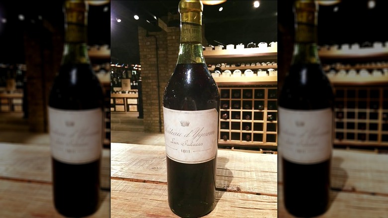 Bottle of 1811 Chateau d'Yquem on a wooden table, in front of other bottles of wine