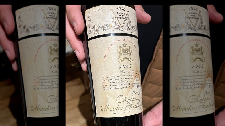 Hand holding a bottle of 1945 Château Mouton-Rothschild