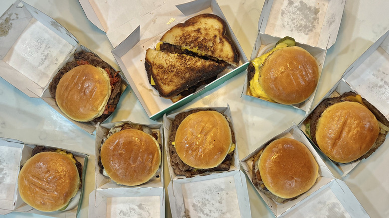 8 different Wahlburgers burgers in to-go containers.