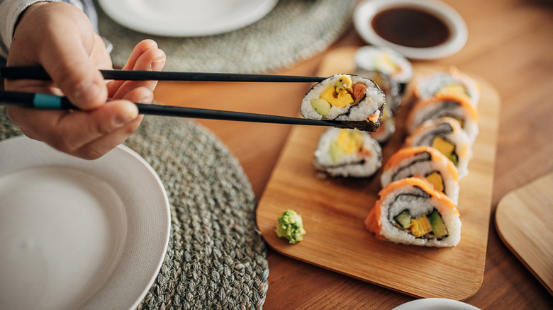 Person eating an elegant assortment of sushi with chopsticks