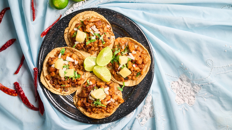 Four tacos on a decorative plate
