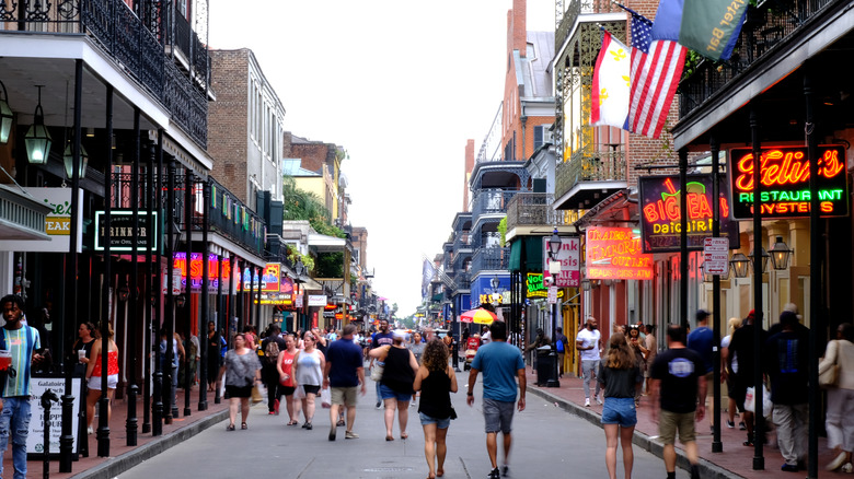 Flashy restaurant signs and tourists on Bourbon Street in New Orleans