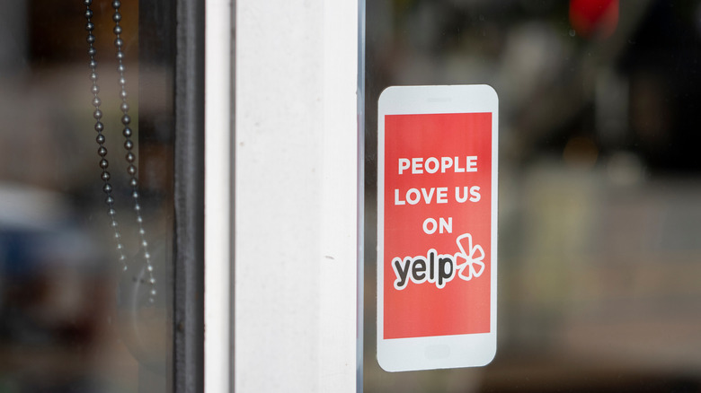 A "People love us on Yelp" sign shaped like a smartphone on a restaurant window