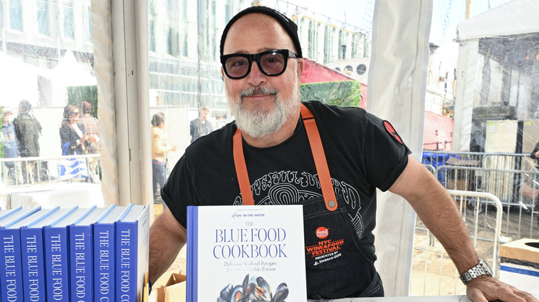 Andrew Zimmern posing with copies of his book The Blue Food Cookbook
